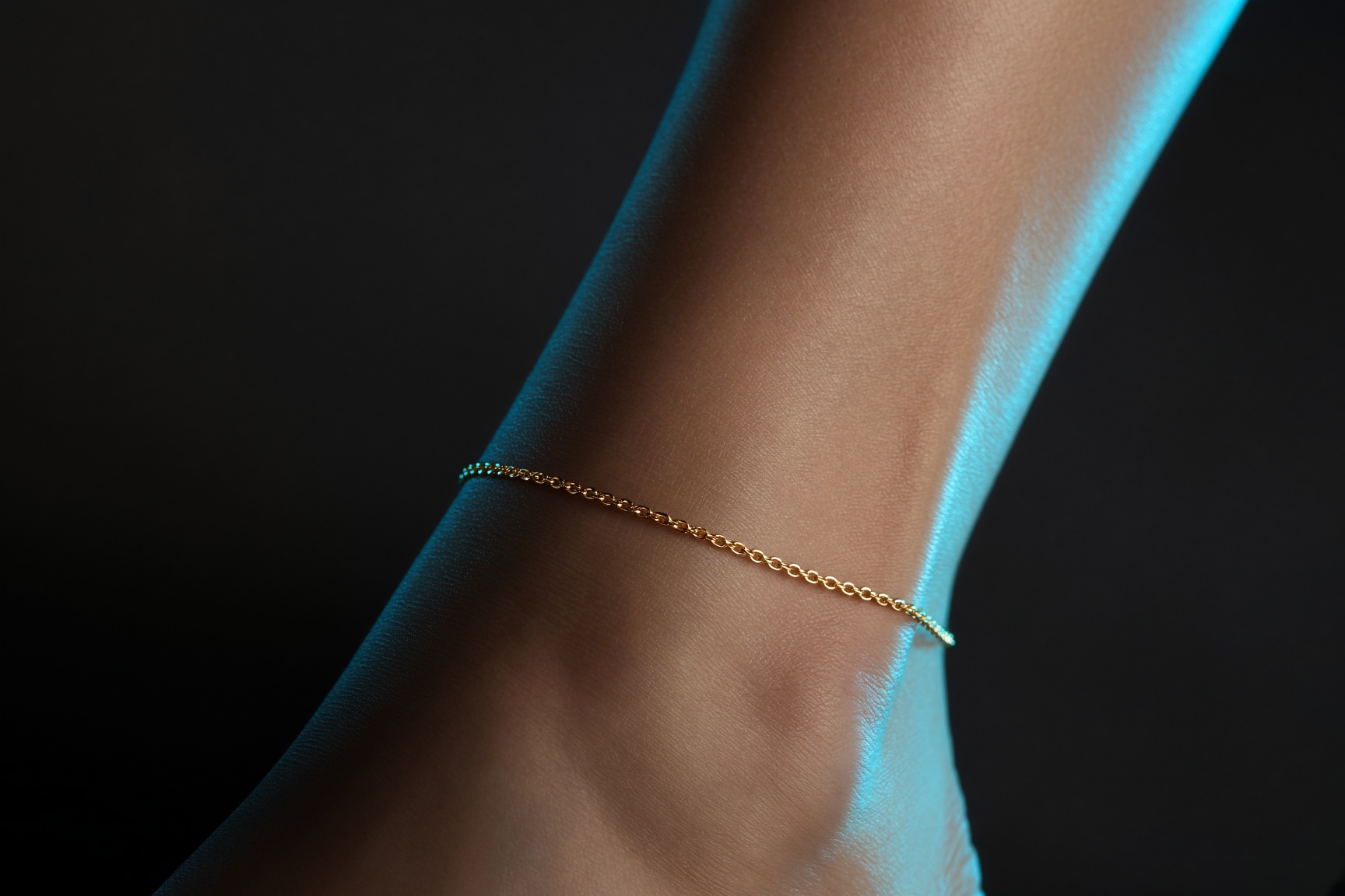 Fine gold anklet chain against black